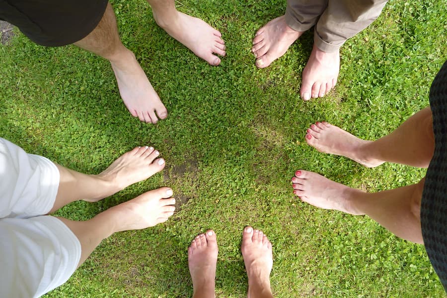 Voeten van meerdere verschillende mensen op een grasveld.